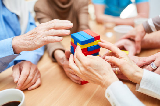 Group of seniors with dementia builds a tower in the nursing center from colorful building blocks