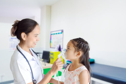 Medical doctor applying medicine inhalation treatment on a little girl with asthma inhalation therapy by the mask of inhaler.