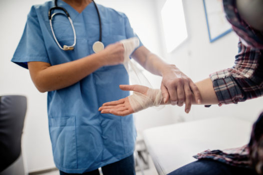 Close up of orthopedist putting bandage on broken hand, Selective focus on hand